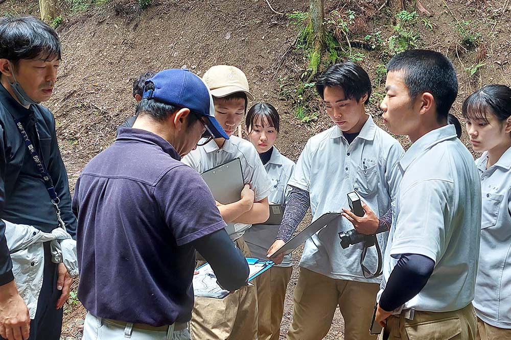 林の様子を観察し意見を交わす高校生たち