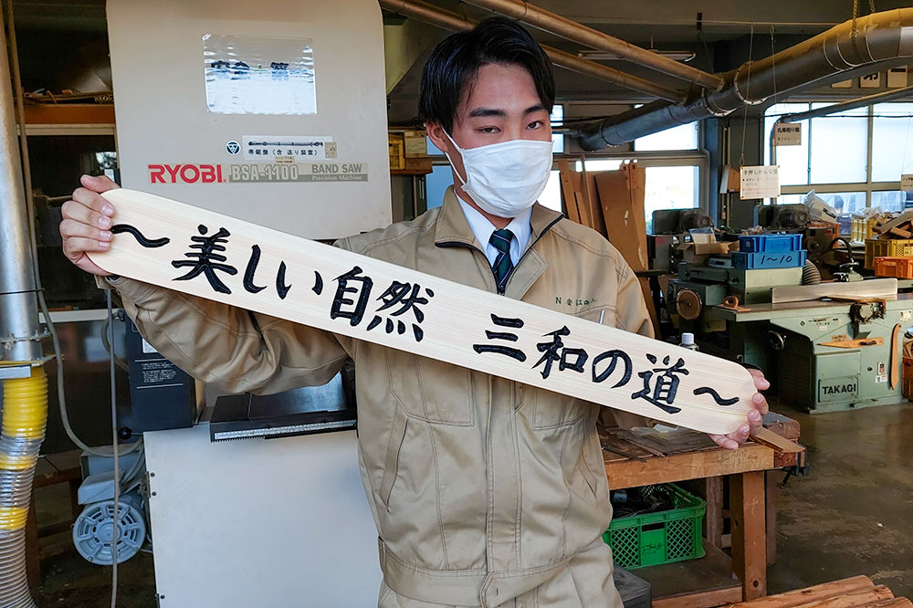 完成した林道看板を持つ高校生