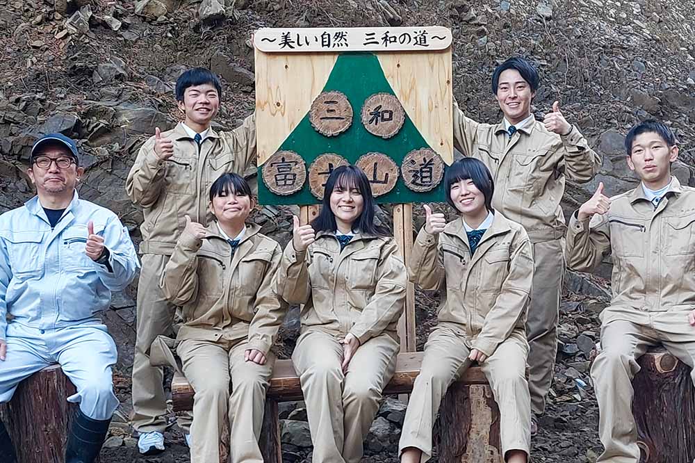 設置完了後に看板の前でポーズを決める高校生たち