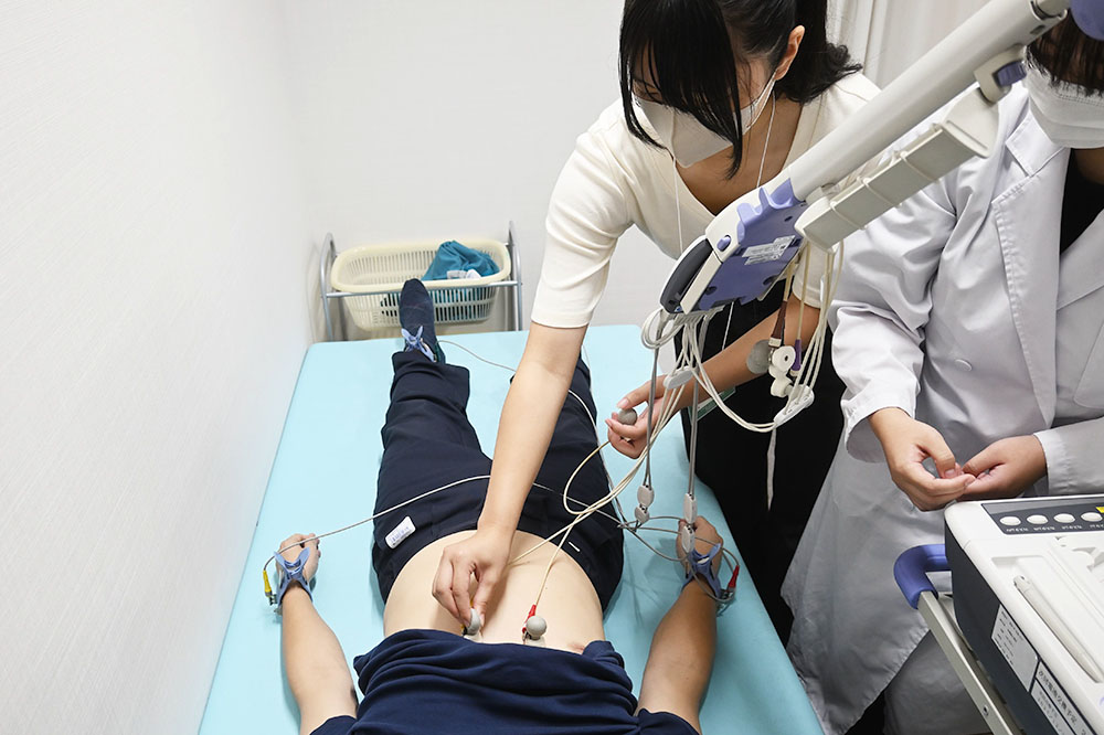 医療技師の指導により心電図を体験している様子