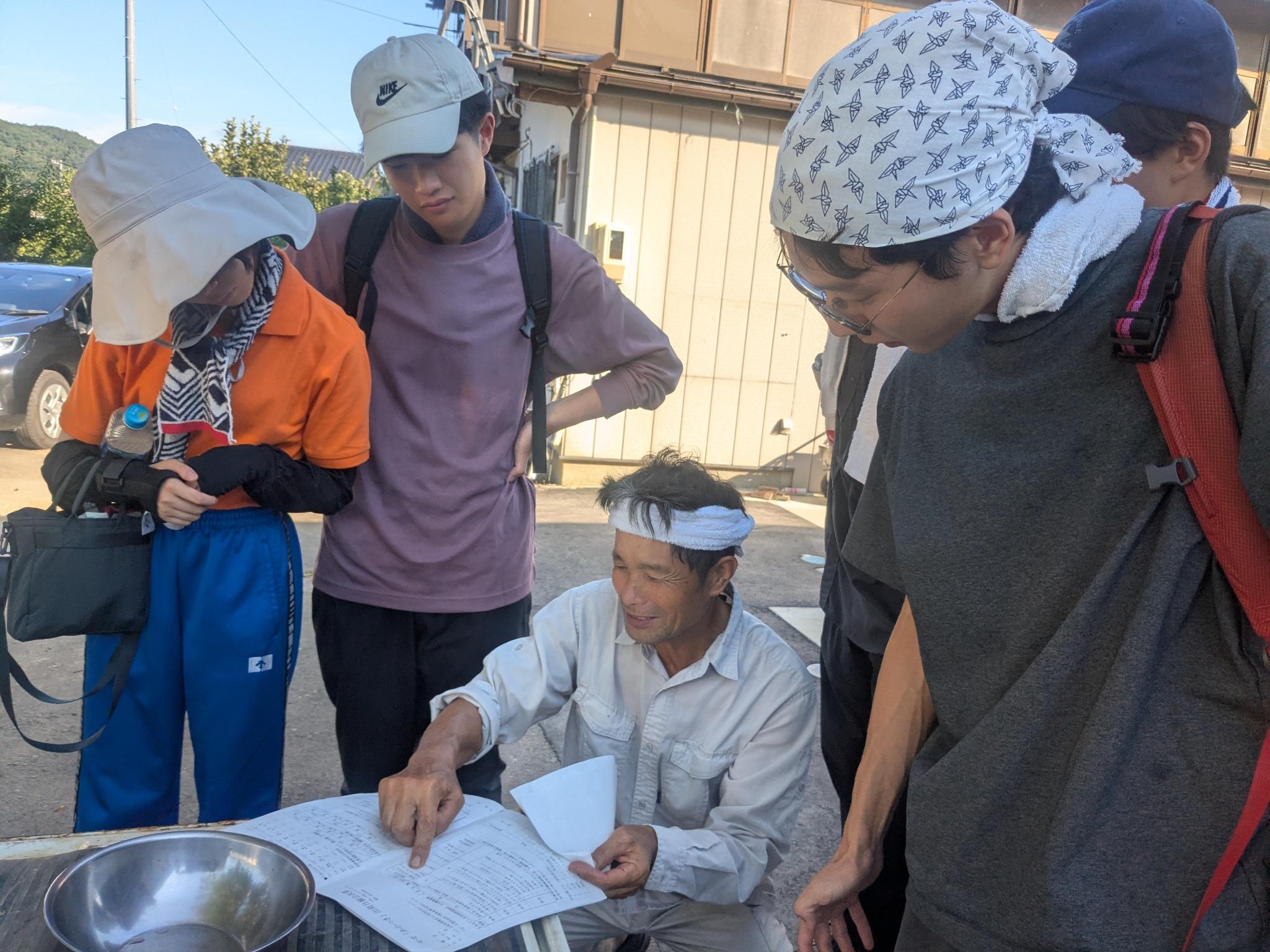 桃畑で栽培方法について生産者から説明を受ける学生