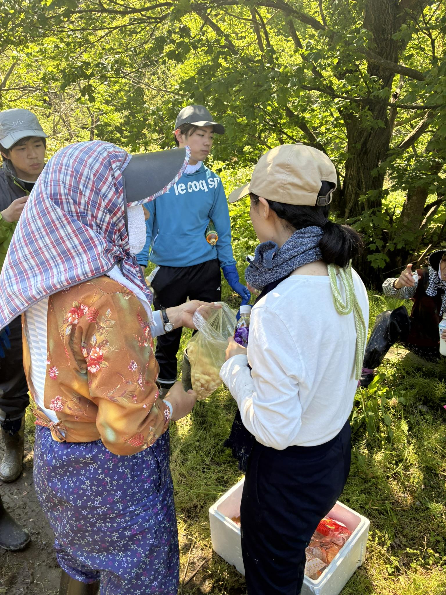 鍋倉集落で田植えの休憩中に地域住民と交流する学生