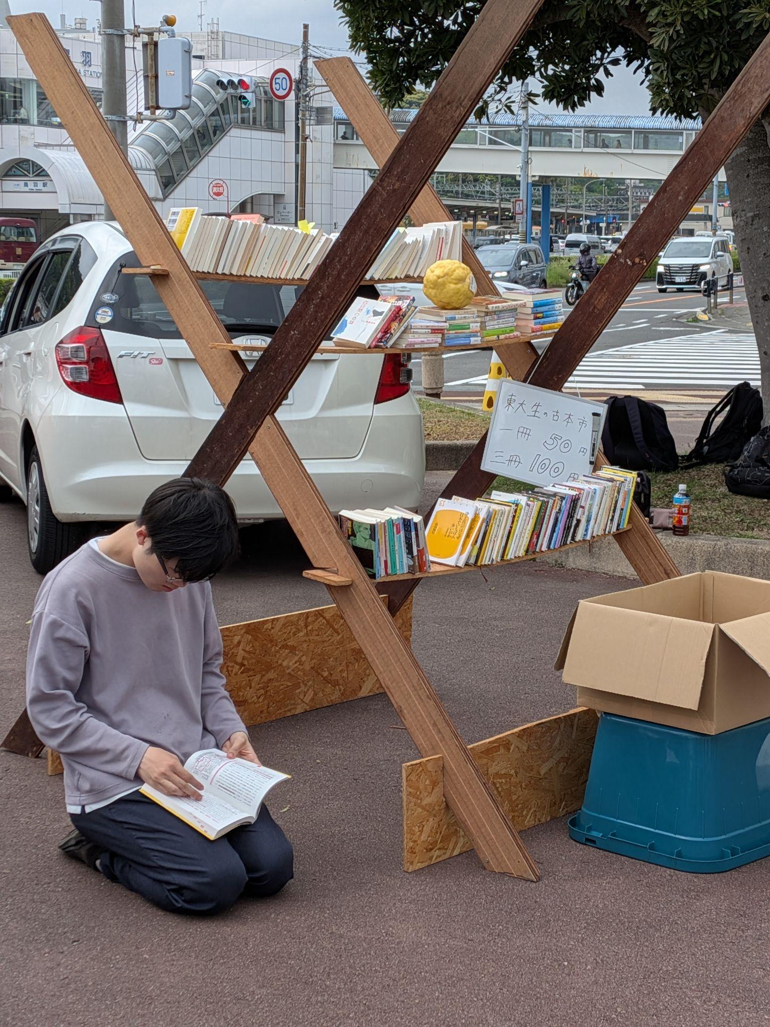 鳥羽駅前の古本市で本を並べる学生