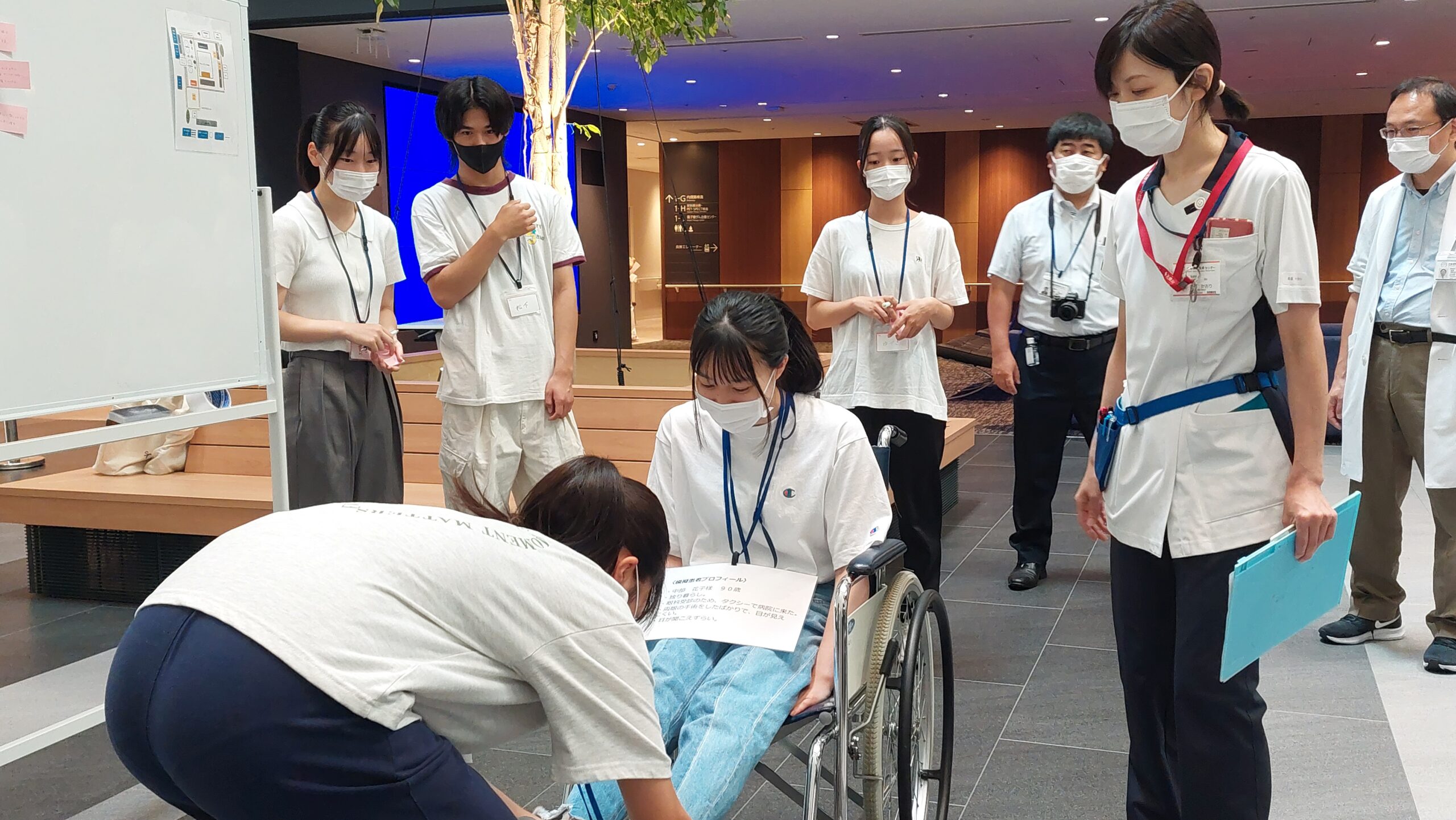 車椅子に乗る高校生の足元を確認しながら体験を進める様子