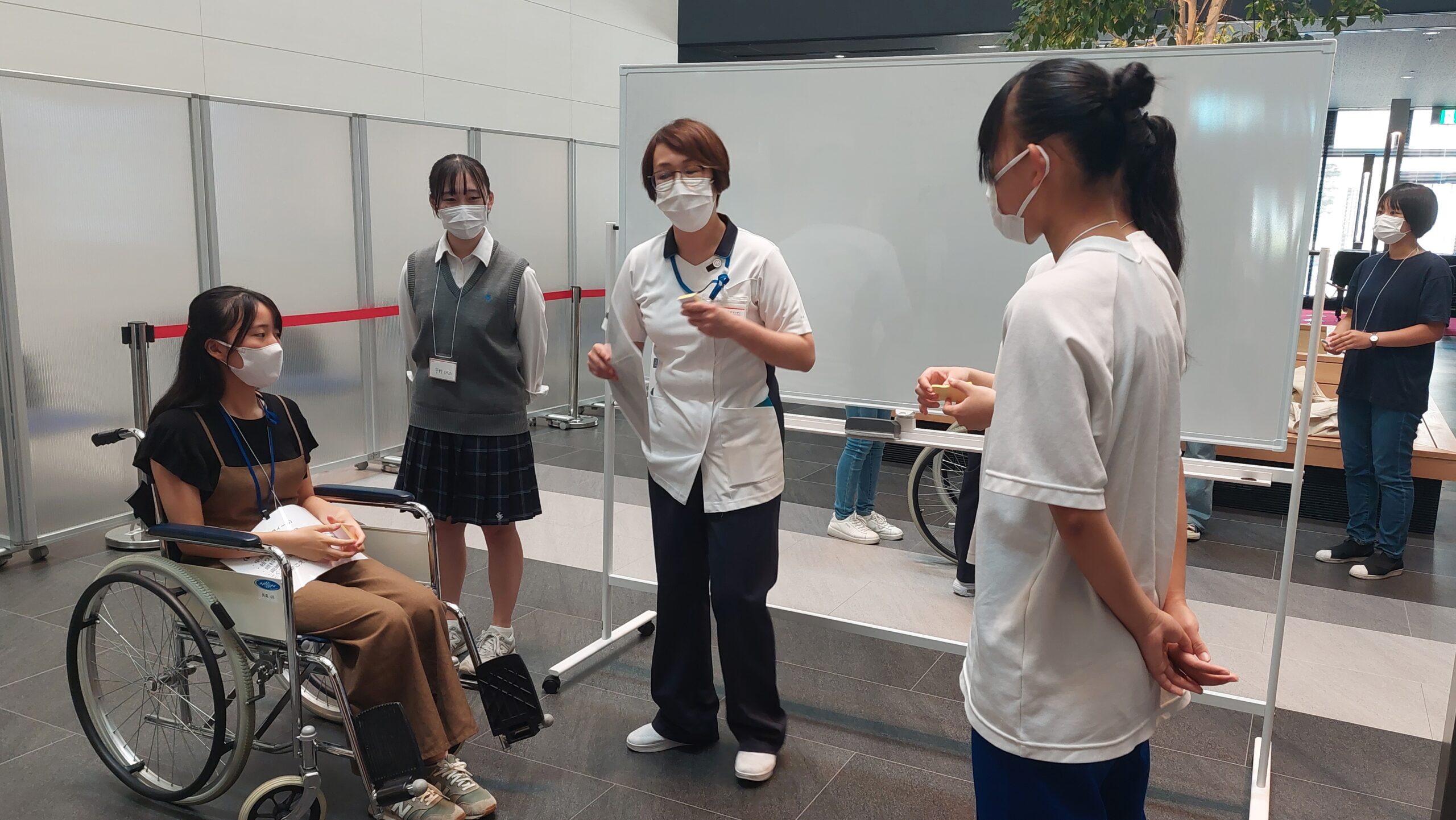 車椅子に乗る高校生と看護師が、体験について話している様子