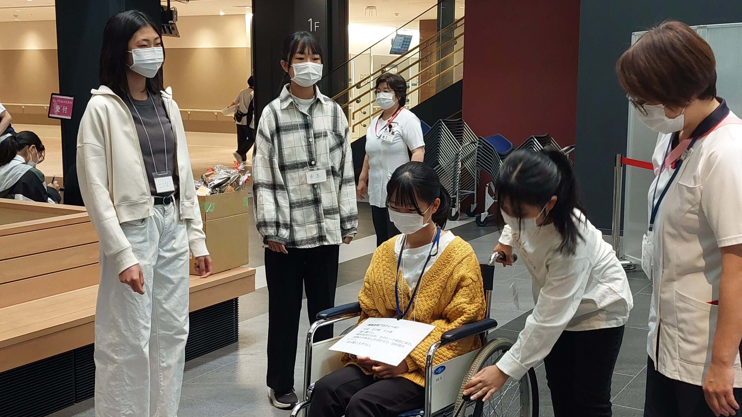 車椅子に乗る高校生と操作する高校生を看護師が見守る様子