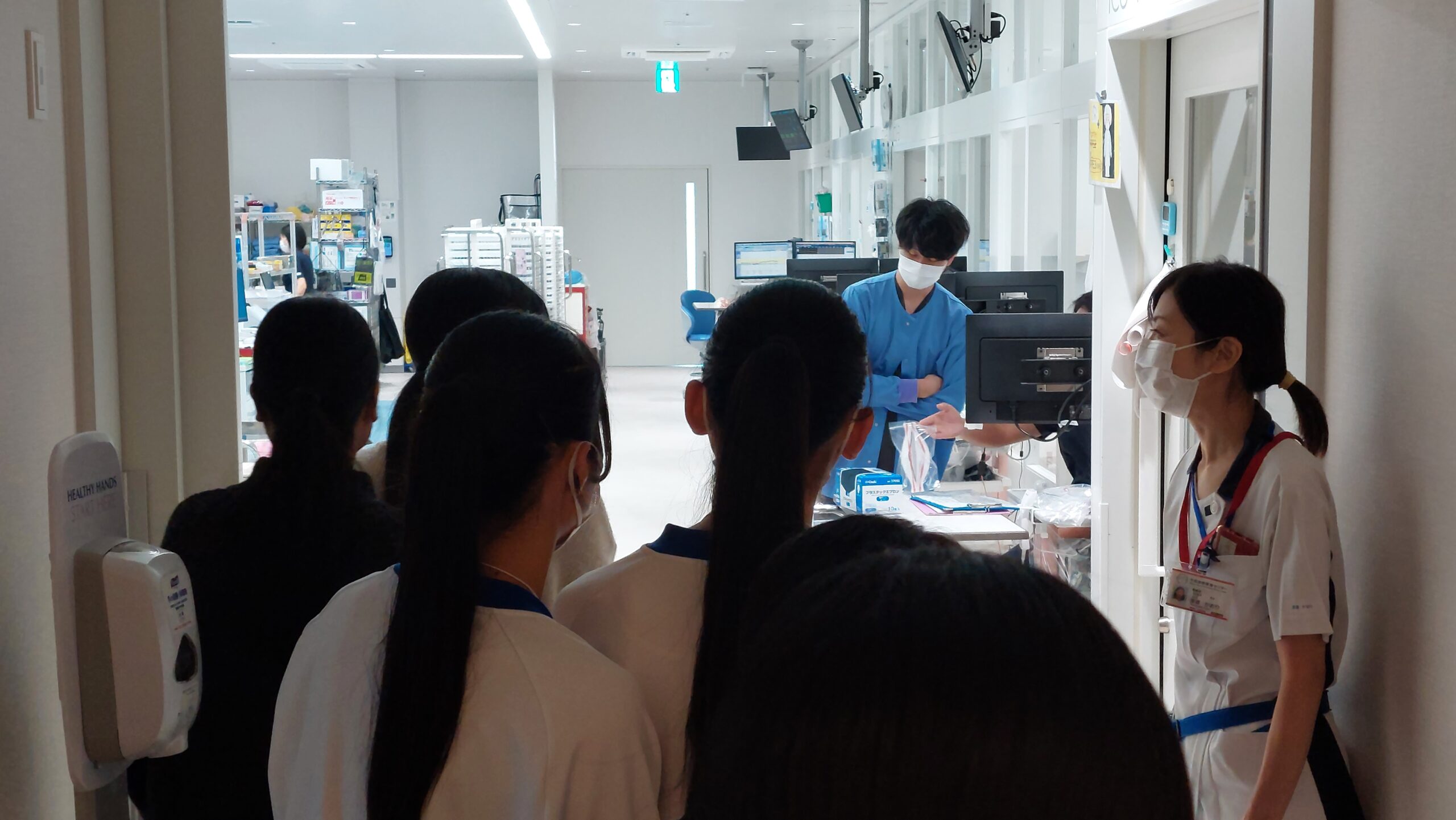 医療現場を見学しながら看護師の説明を聞く高校生