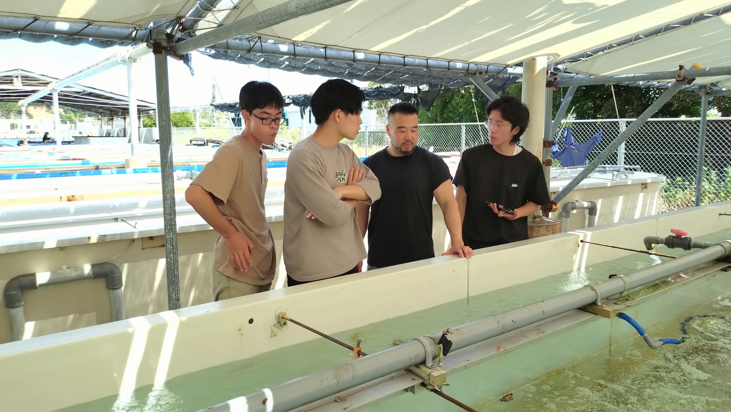 水産技術センターで水産資源の育成設備を見学する学生