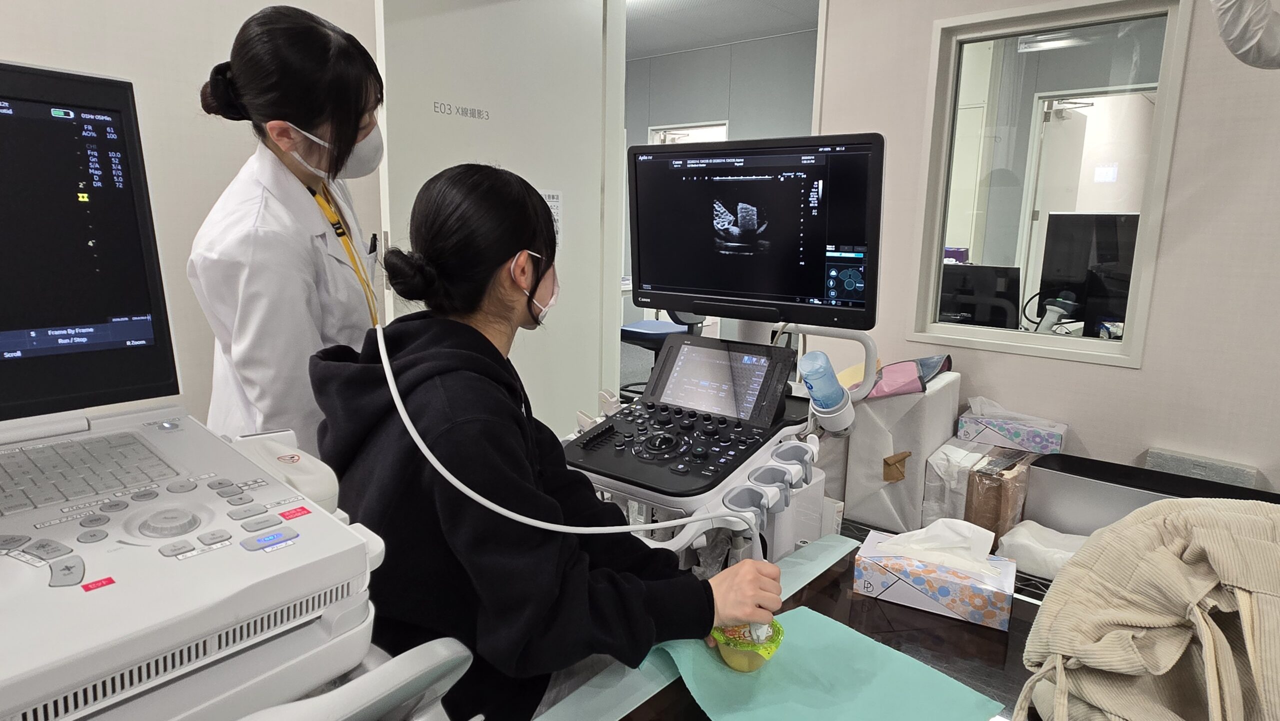 臨床検査技師の指導を受けながら超音波検査を体験する高校生