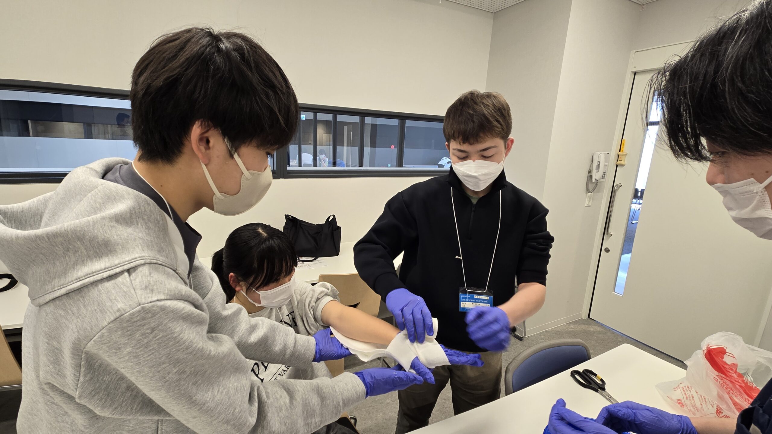 医師の指導を受けながらガーゼや包帯を使った処置を体験する高校生