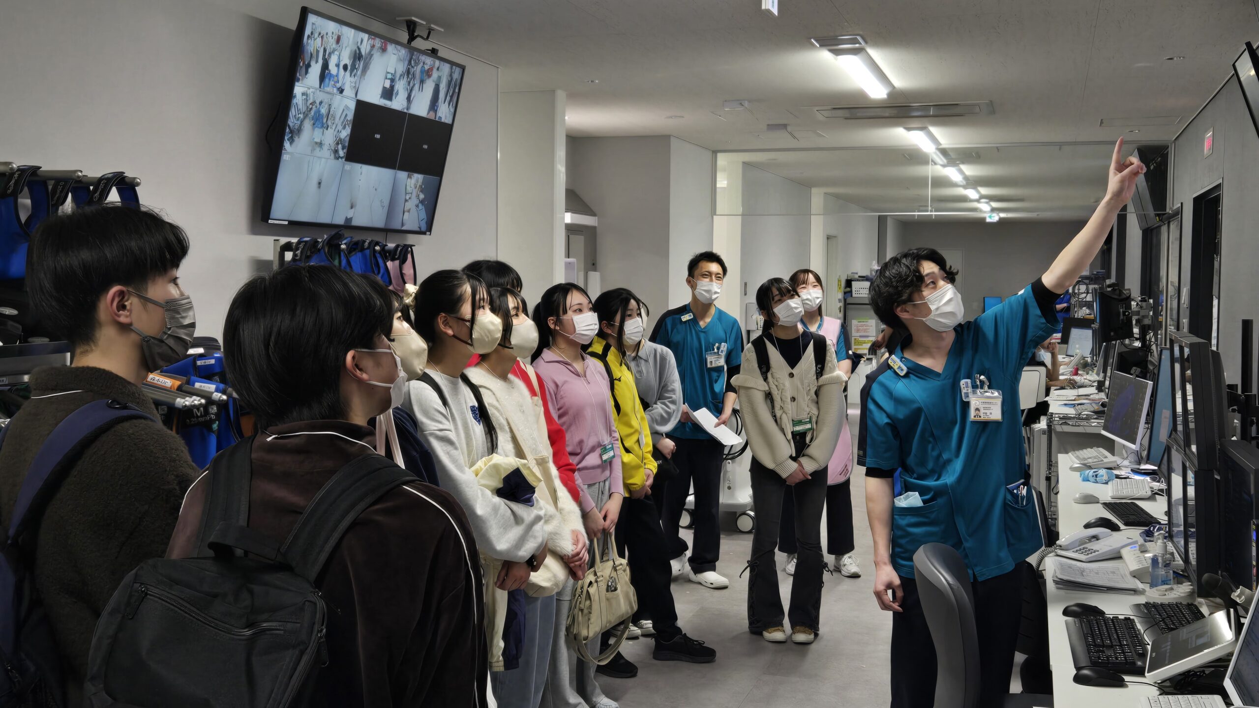 集中治療室で看護師から設備や看護の役割について説明を受ける高校生