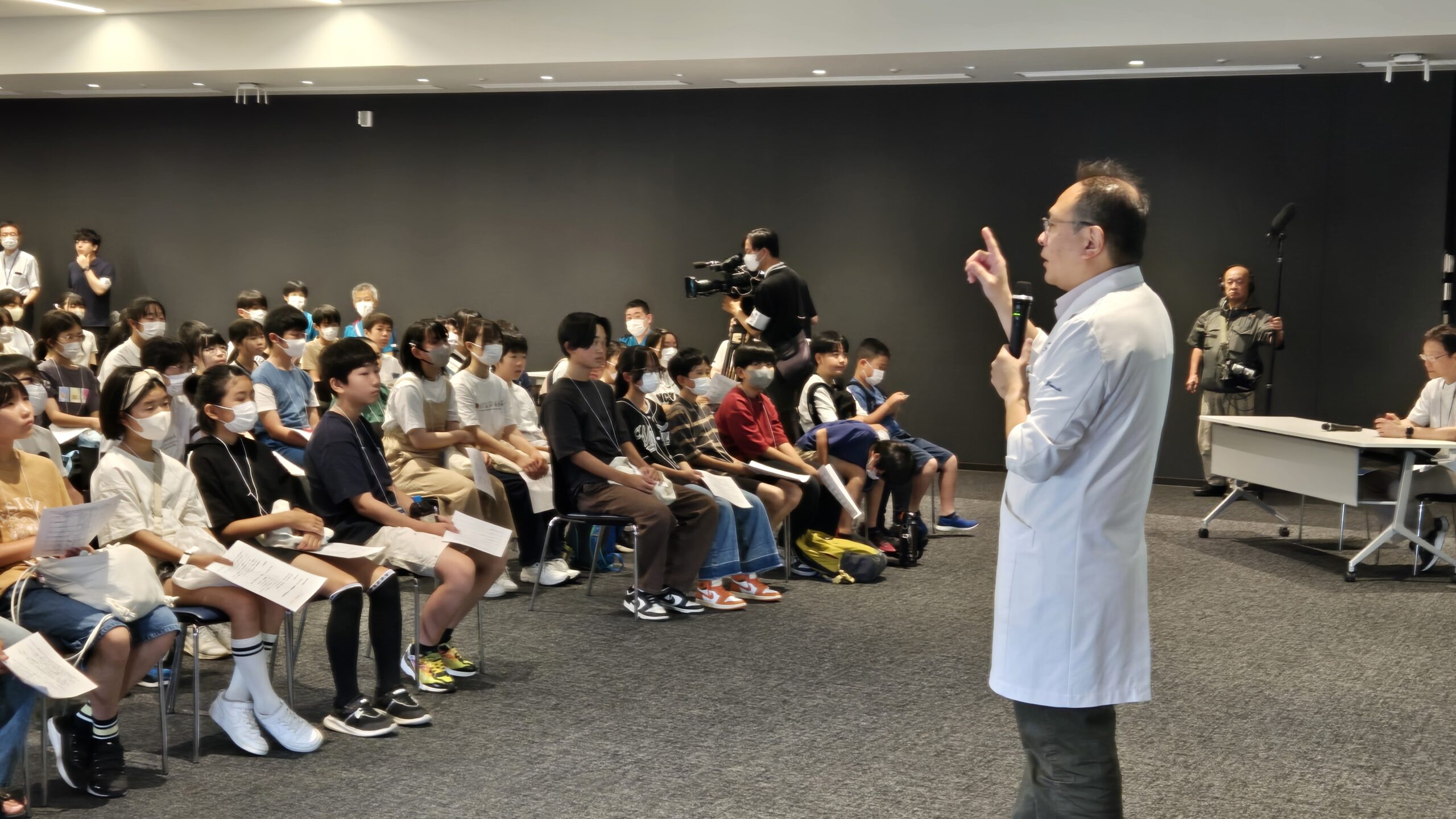 オープンホスピタルの開会時に医師から説明を受ける小中学生