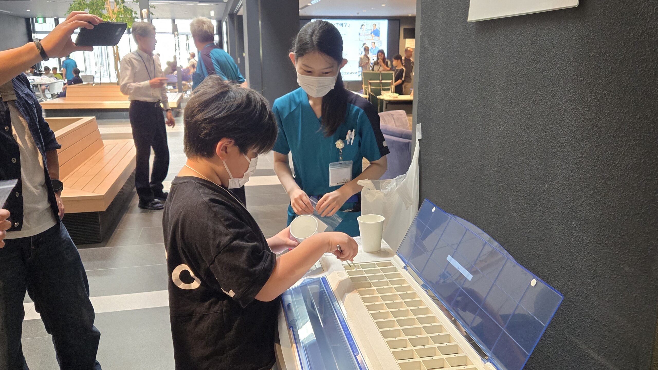 薬剤師の説明を受けながら薬の調剤を体験する小学生
