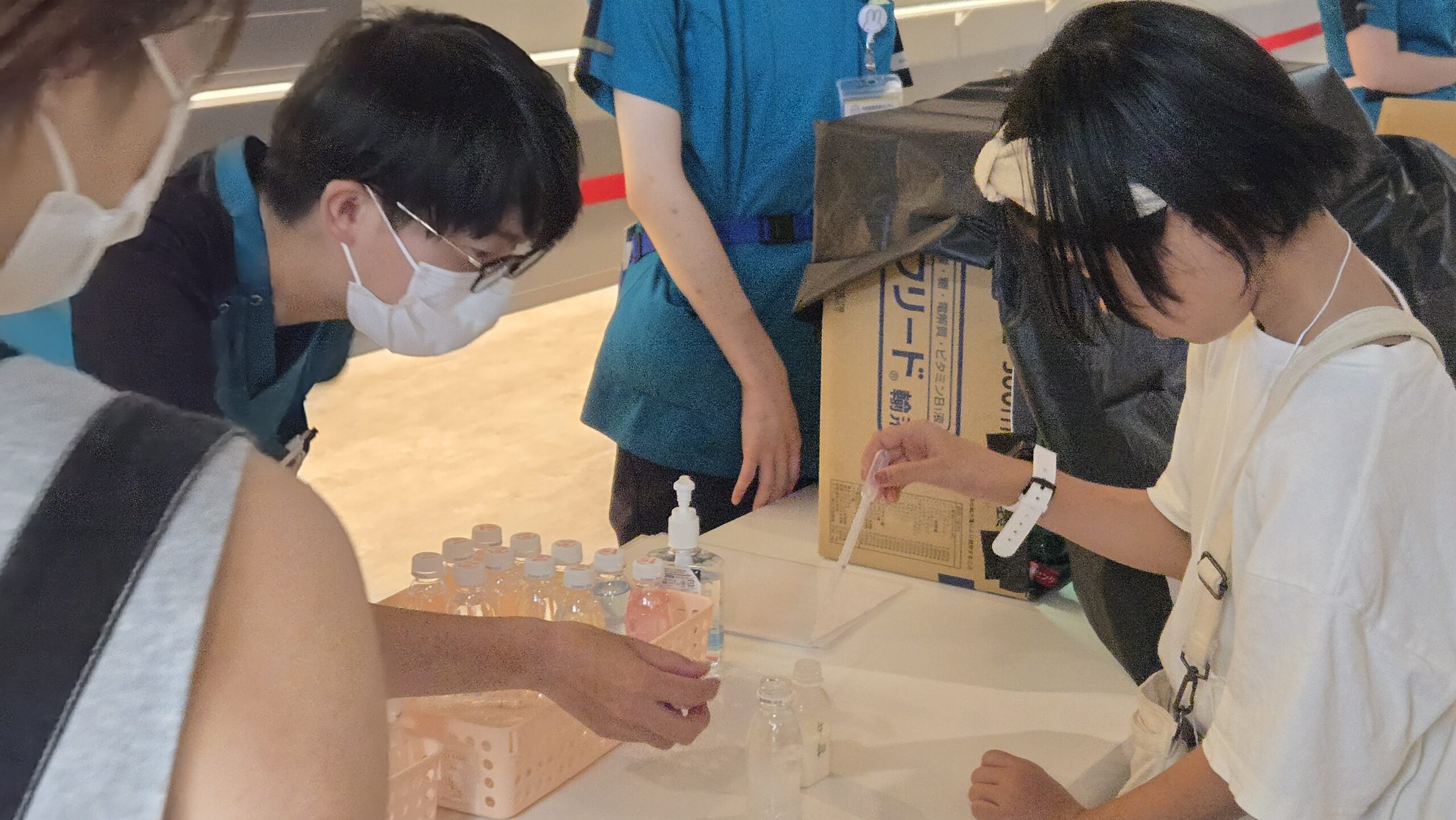 薬剤師の指導を受けながら液体を量る小学生