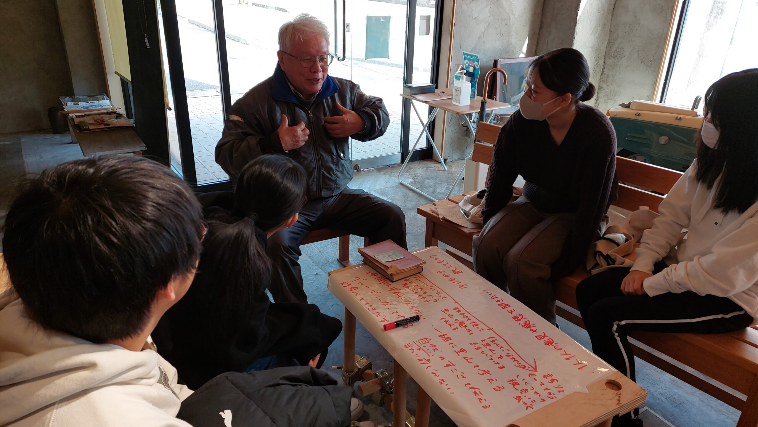 授業の流れを大きなシートに書き出しながら日比野安平先生と話し合う高校生