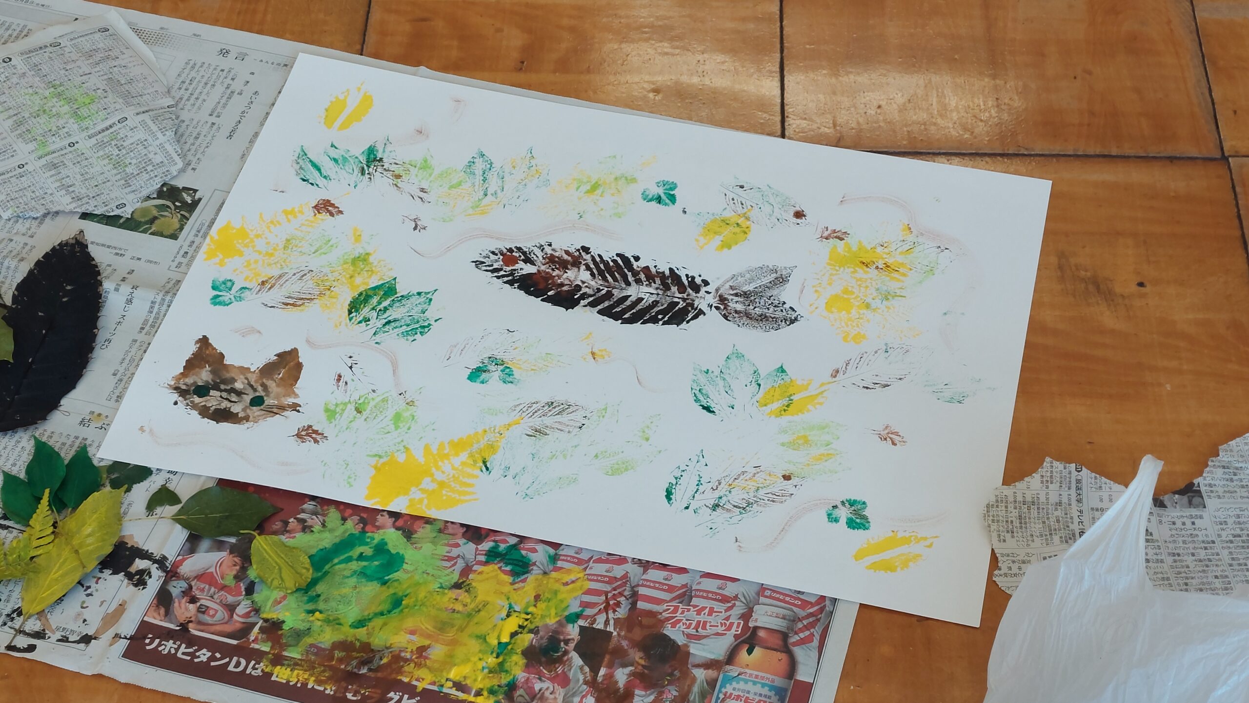 自然の葉を使って作品づくりを行う三和小学校の児童と加茂高校の高校生