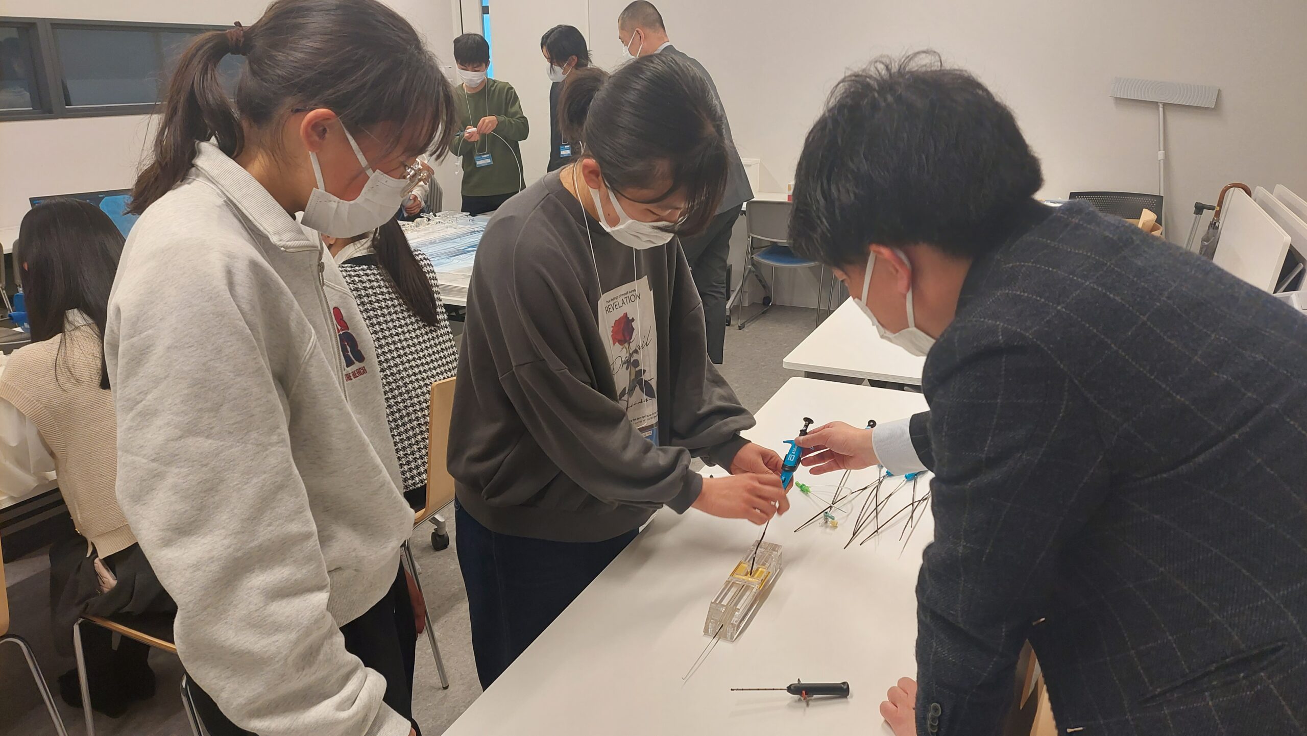 医師の指導を受けながら医療シミュレーターを使った体験に取り組む高校生