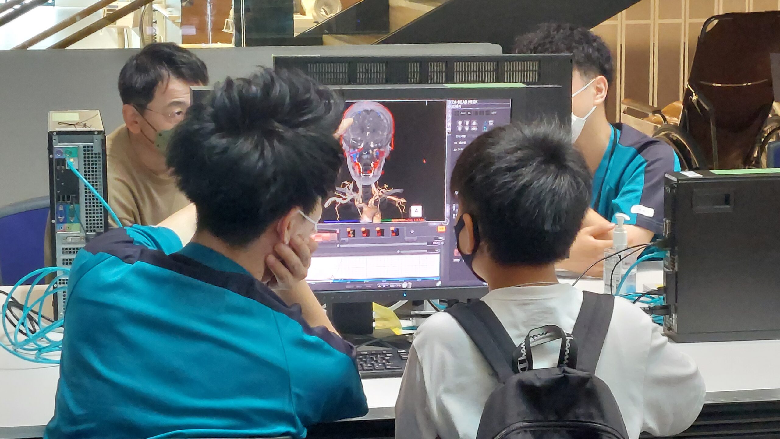 医療スタッフとともに脳の3D医療画像を見る小中学生