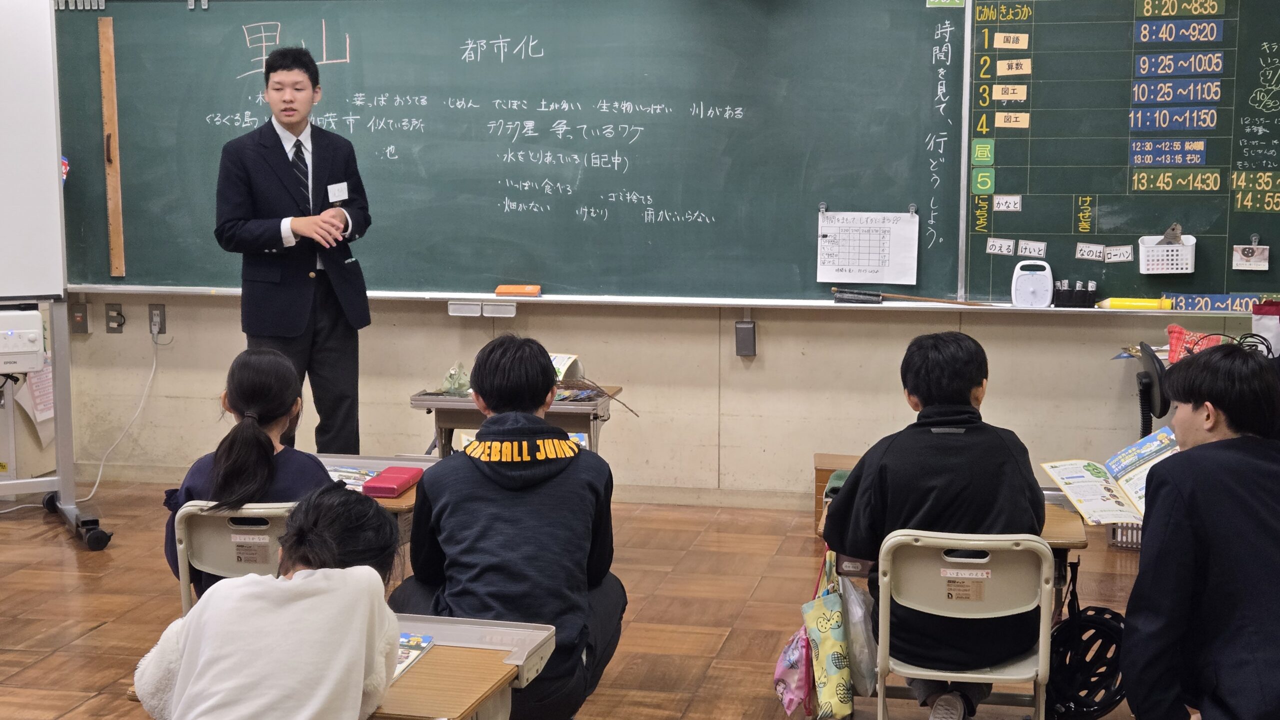 高校生がマンガ教材を示しながら小学生と一緒に内容を考える授業