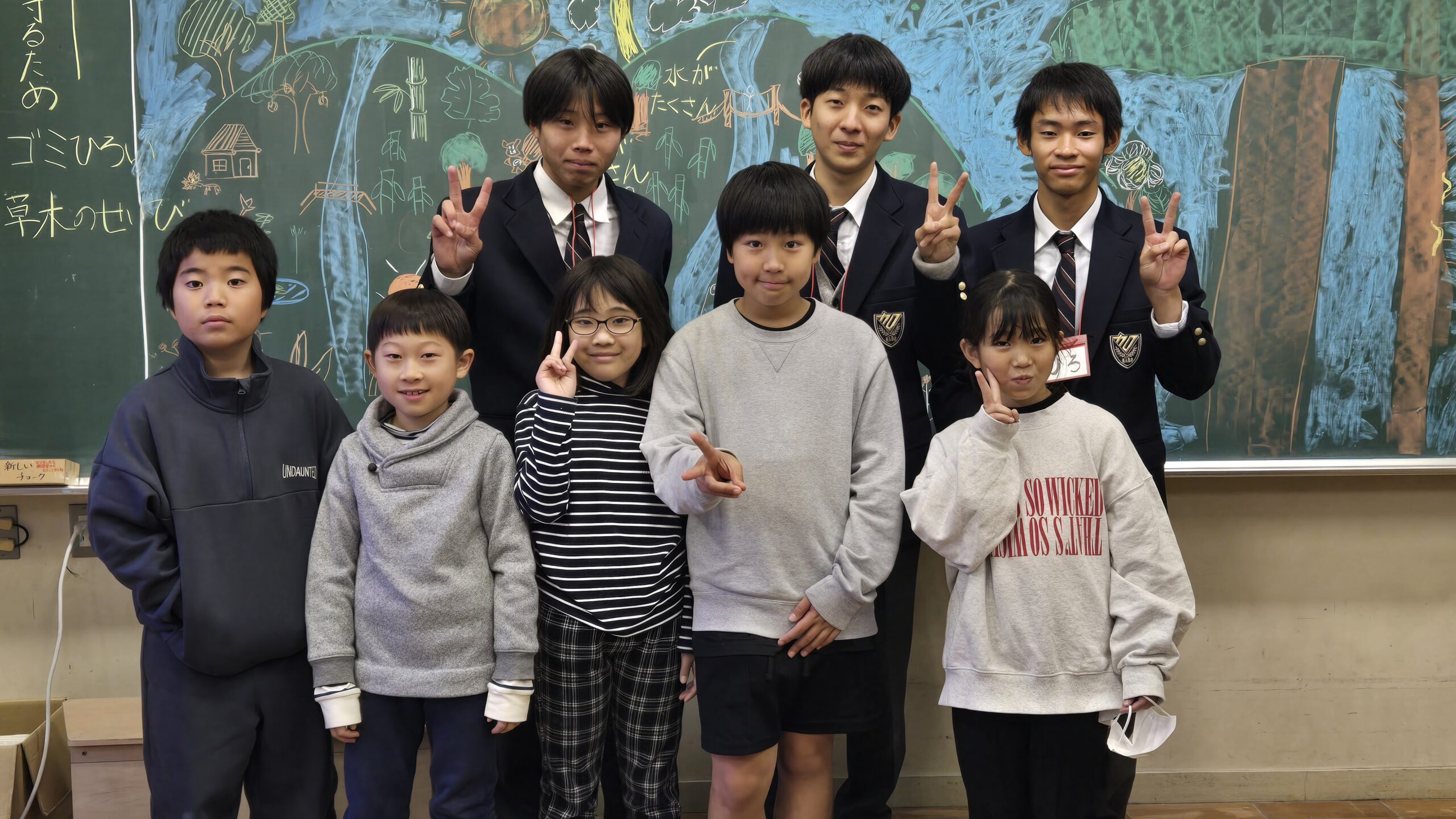 林道で見た自然を黒板に描く小学生と高校生
