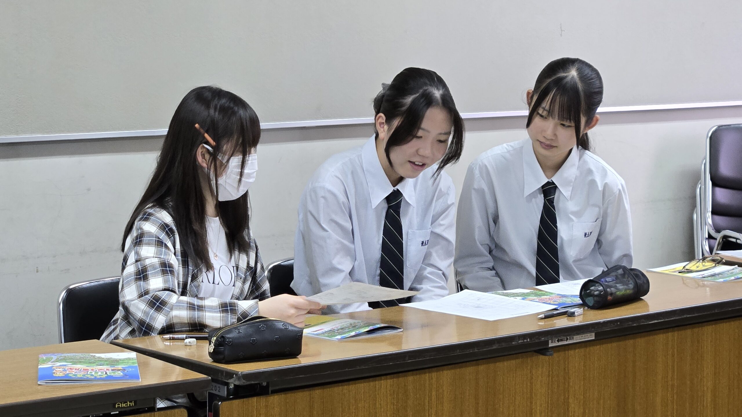 マンガ教材を見ながら授業のアイデアを話し合う高校生