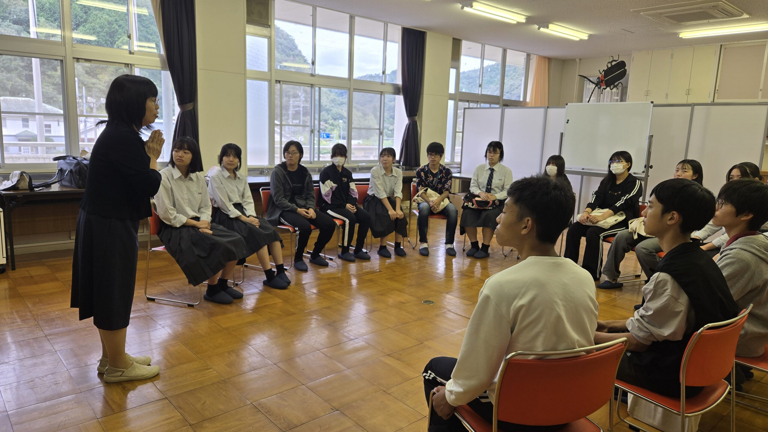 三和小学校の遠藤校長を囲み子どもとの接し方について話を聞く高校生たち