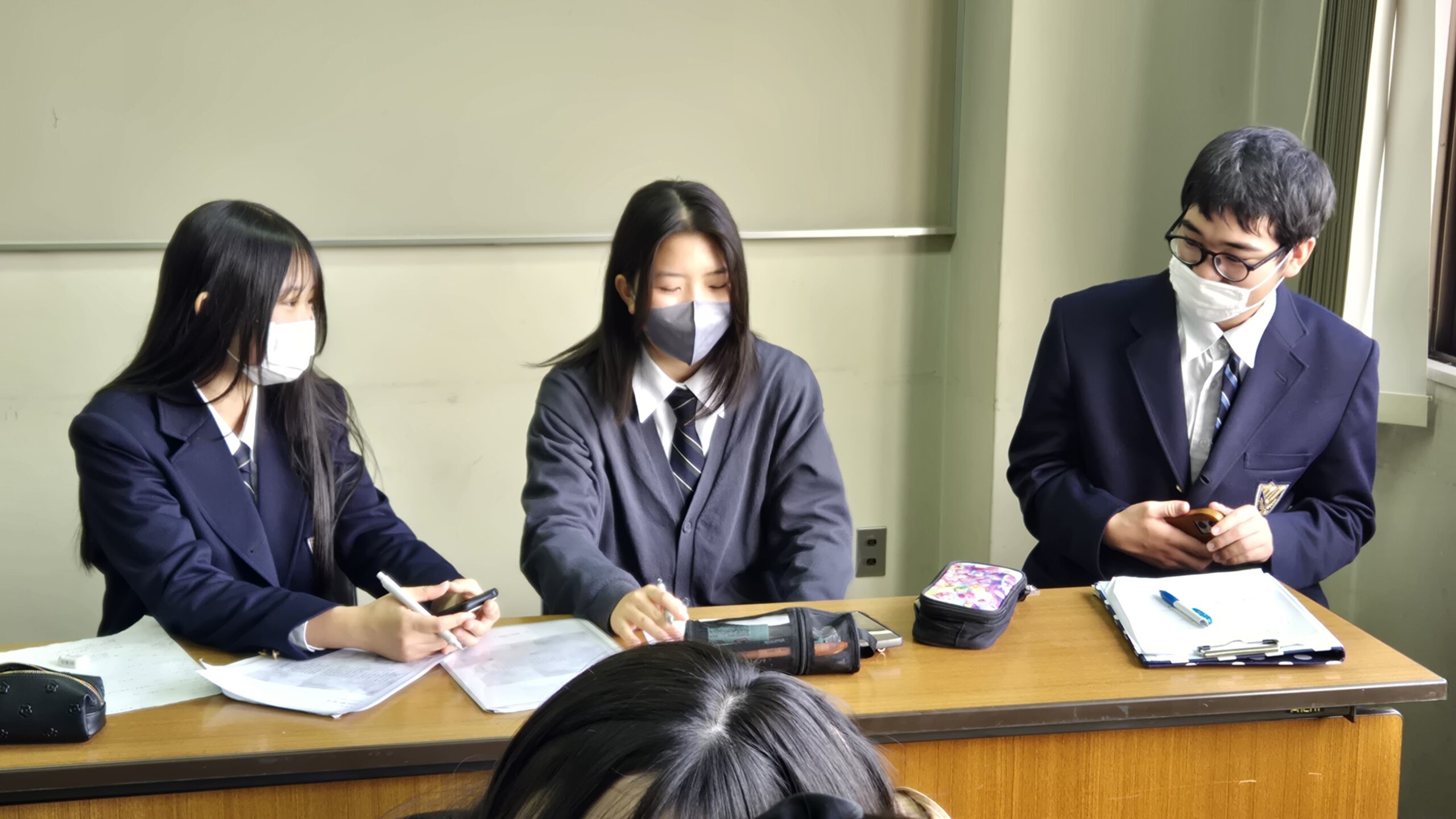 資料を見ながら授業計画について話し合う高校生たち