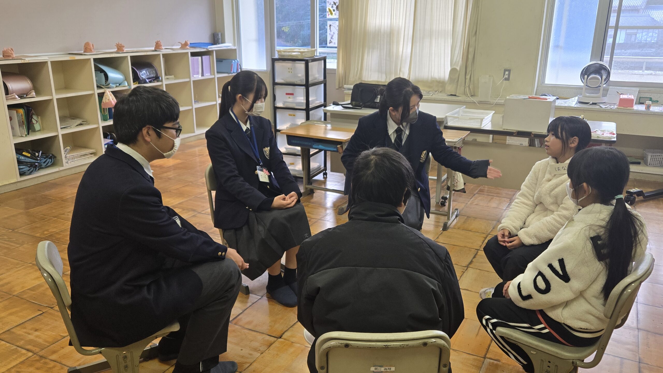 輪になって高校生と小学生が話をする様子